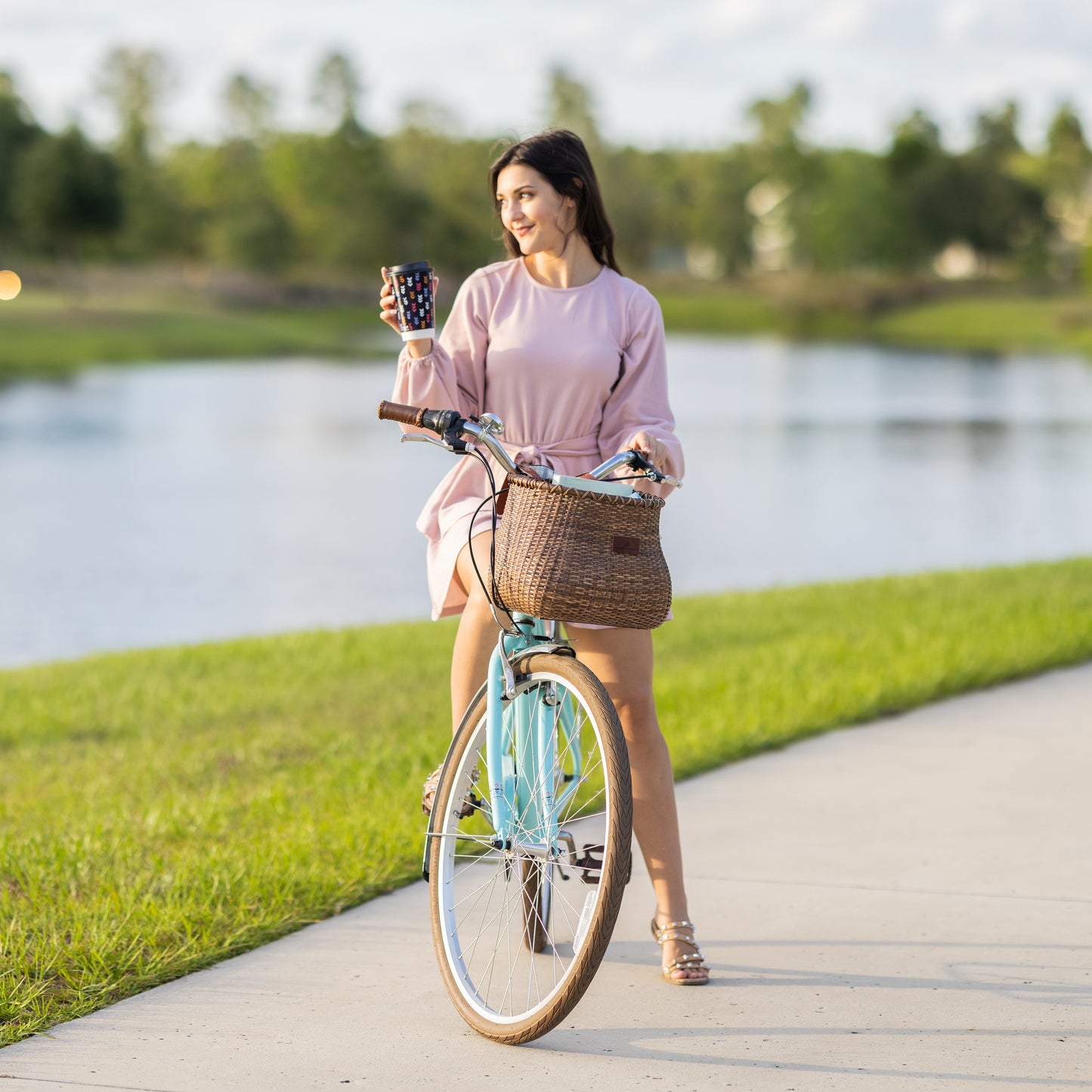 young lady riding bike with a coffee and a Warners Wheels bike basket front attached to her bike