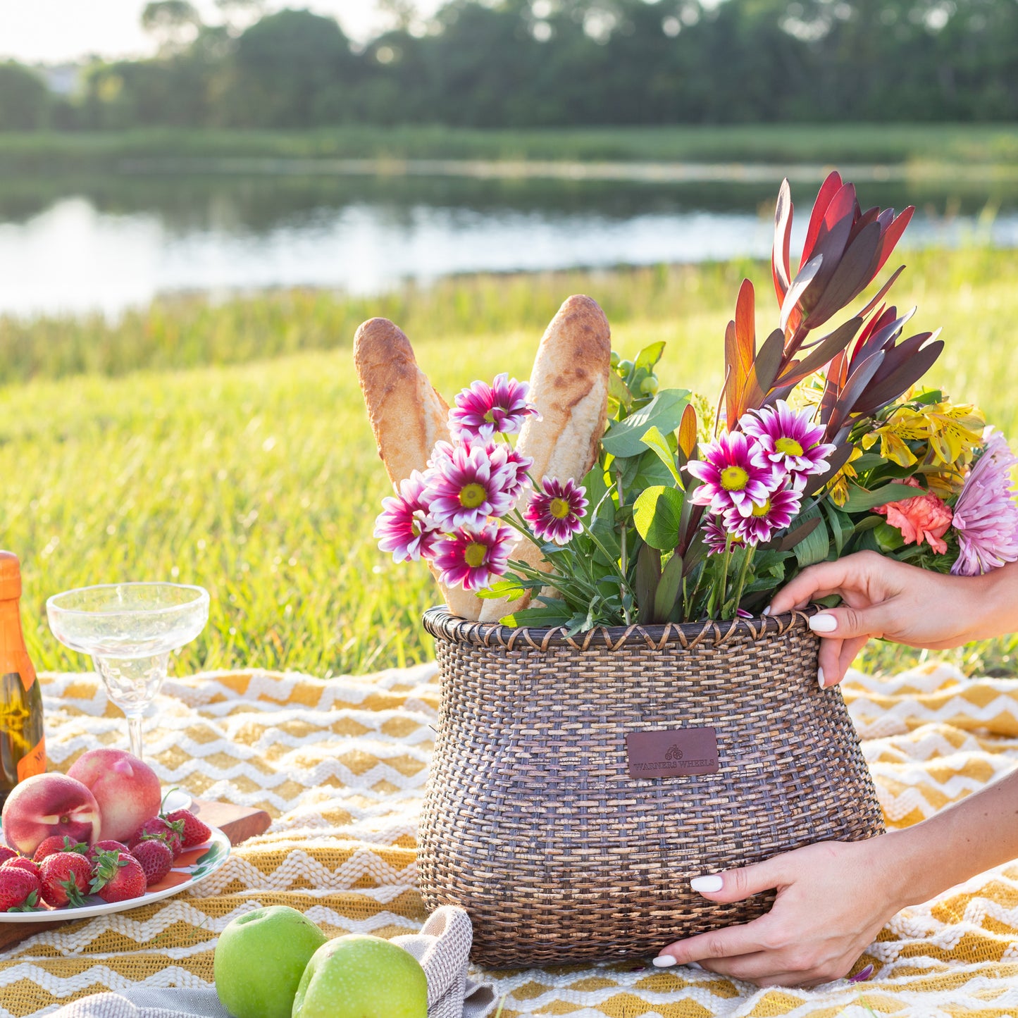 Bike Basket full of flowers being placed down on a picnic rug as a decoration
