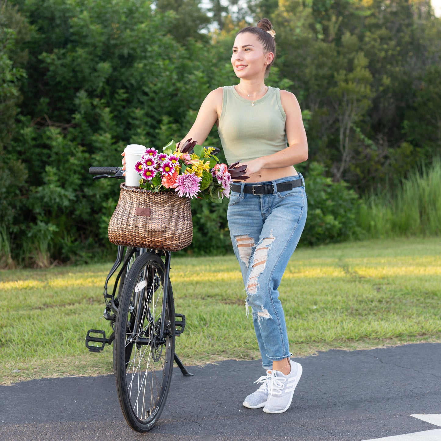 Bike Basket holding flowers being pushed by a lady holding a coffee